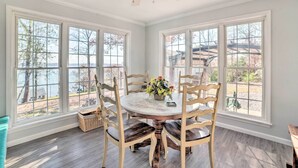 A dining area with a round table, six wooden chairs, and a vase of flowers. - Country-Chic Home w/ Fire Pit, Steps to Lake! (New Concord)