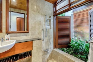 A bathroom with a shower, sink, and wooden vanity.