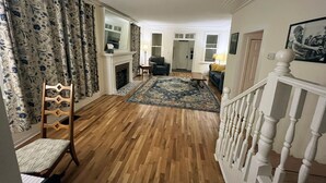 Ein geräumiges Wohnzimmer mit Holzboden, Kamin, Sofa und Treppe.