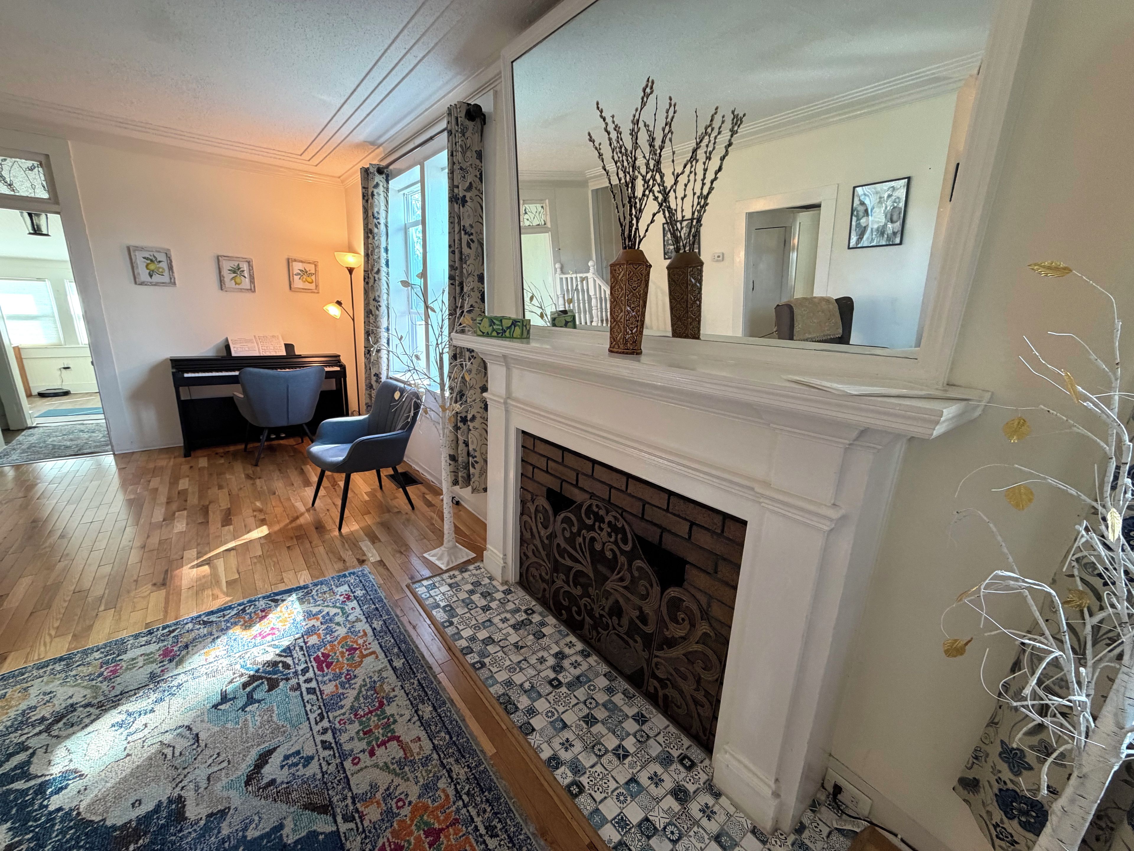 Una sala de estar con chimenea, un piano y un espejo grande.