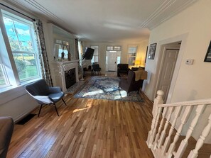 A spacious living room with a fireplace, a large rug, and a television. - Old Florida Charm (Eustis)
