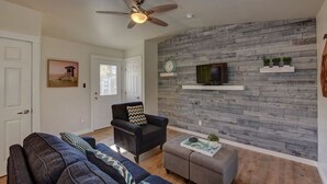 Ein Wohnzimmer mit einem dunkelgrauen Sessel, einem grauen Hocker und einem blauen Sofa.