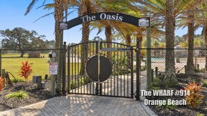 Une entrée fermée par un portail mène à The Oasis, avec une enseigne indiquant « The Oasis » et une autre indiquant « WHARF #914, Orange Beach ».