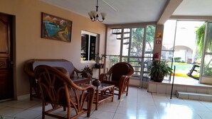 Una habitación con sofá, sillas, una mesita y un cuadro en la pared.