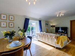 A room with a dining table, chairs, a sofa, a TV, and a door leading outside.