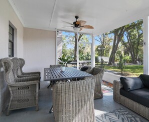 A covered patio with wicker furniture, a ceiling fan, and a view of the surrounding greenery. - Rustic Hideaway - Modern Estate - Great Location + Pet Friendly! (Windermere)