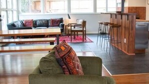 A spacious living area with a green sofa, a wooden coffee table, and a dining area with a bar. - Sunny Mid-Century Gem (Arcata)