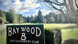 A sign for Baywood Golf & Country Club with a view of a golf course and trees in the background. - Sunny Mid-Century Gem (Arcata)