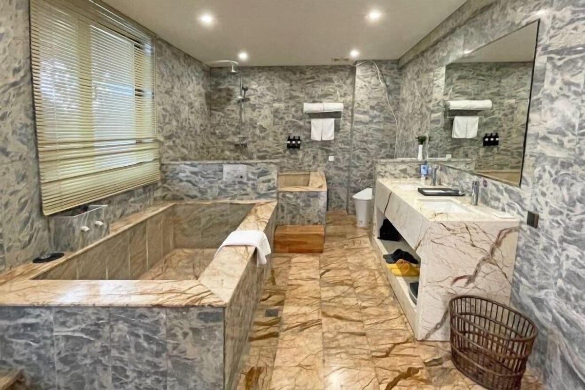 A bathroom with a marble sink, a bathtub, and a shower area.