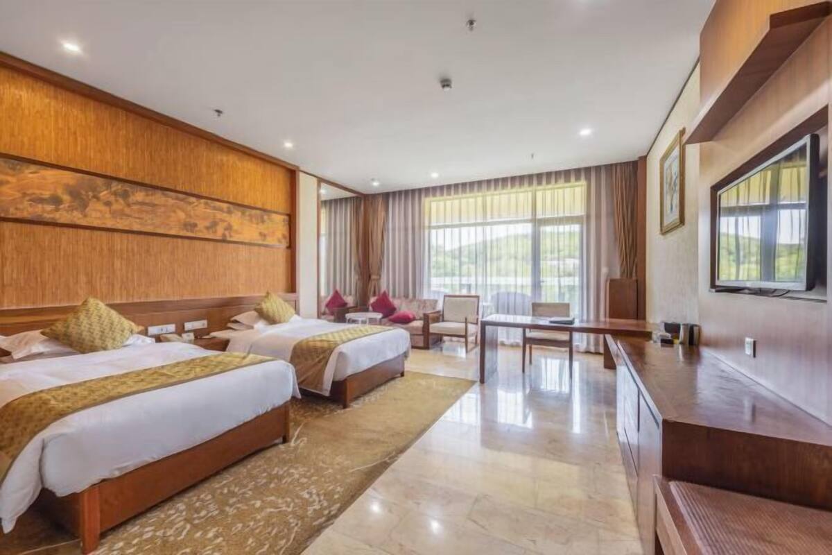 A hotel room with two beds, a desk, and a TV.