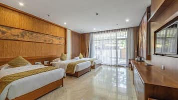 A hotel room with two beds, a wooden headboard, a large window with curtains, a flat-screen TV, and a wooden desk.
