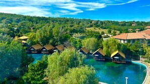 A resort with overwater bungalows, a swimming pool, and a lush green landscape. - Holiday Inn Hongxigu Hot Springs, Gaizhou, Yingkou (Gaizhou)