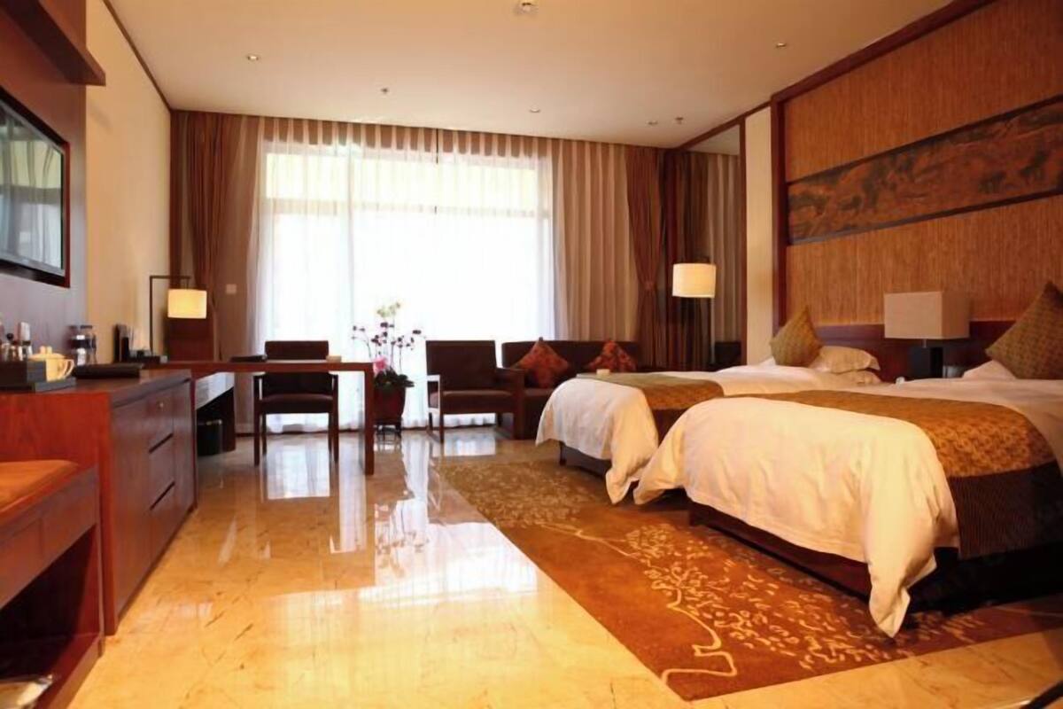 A hotel room with a large bed, a desk, a chair, and a view of the outdoors.