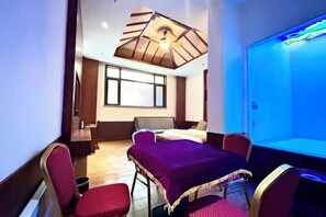 A hotel room with a bed, a desk, a chair, a table, and a large window.