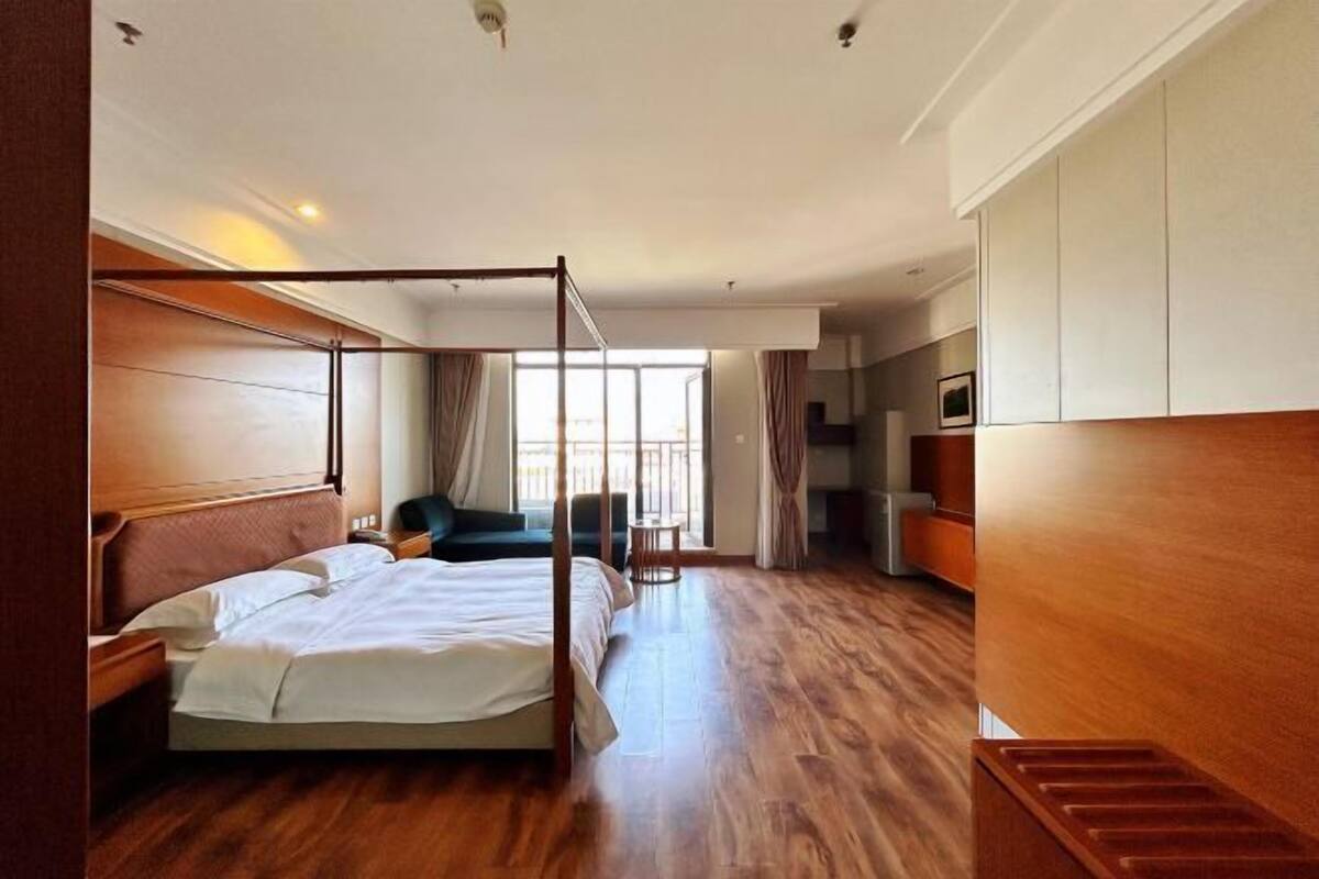 A modern hotel room with a large bed, a seating area, and a view of the outdoors.