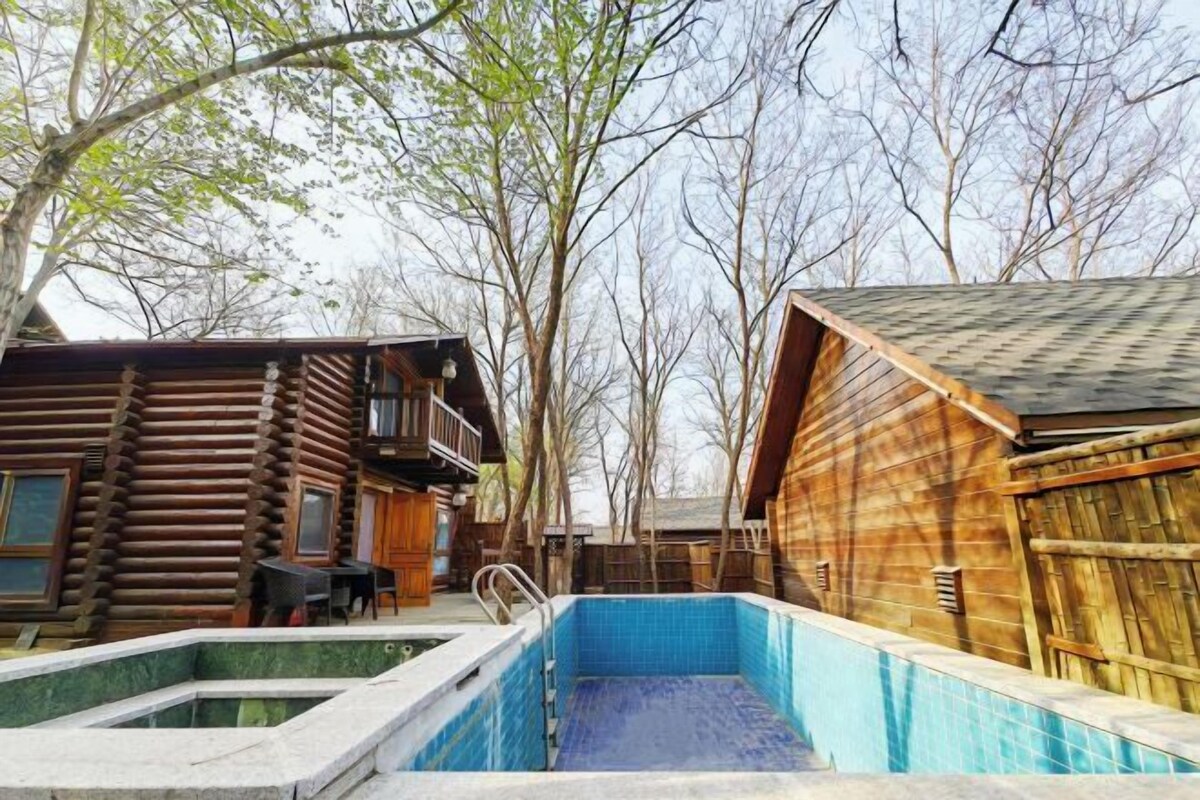A log cabin with a swimming pool, surrounded by trees.