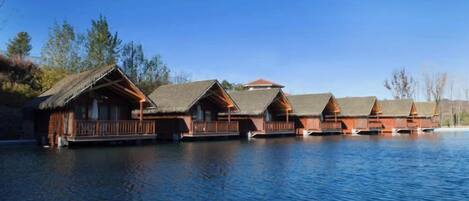 A row of wooden cabins with thatched roofs on stilts over water.