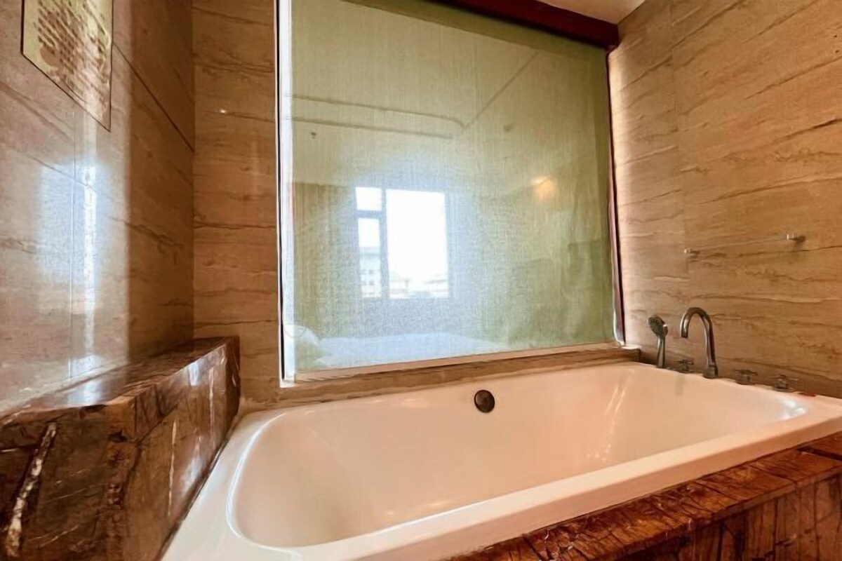 A bathroom with a large bathtub, a window, and a wooden vanity.