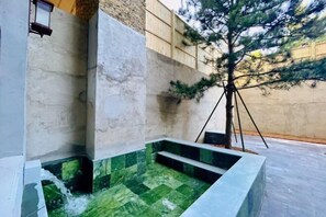 A spa area with a stone wall, a tree, and a small pool. - Holiday Inn Hongxigu Hot Springs, Gaizhou, Yingkou (Gaizhou)