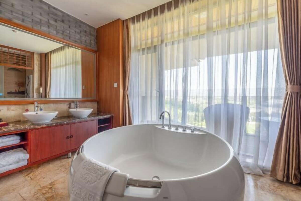 A modern bathroom with a freestanding bathtub, dual sinks, and a large mirror.
