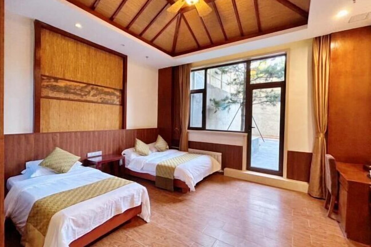 A hotel room with two beds, a large window, and a ceiling fan.