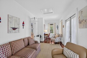 Un salon comprenant un canapé, un fauteuil et un coin repas avec une table et des chaises.