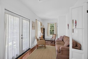Ein Wohnzimmer mit einer Couch, Sesseln, einem Kamin und Blick durch ein Fenster.