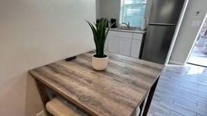 A modern kitchen with a wooden dining table, white cabinets, and a built-in refrigerator. - West University Carriage Home & Parking (Tucson)