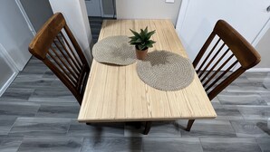 Ein Holztisch mit zwei gewebten Tischsets und einem Blumentopf.