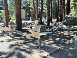 A picnic area with two barbecue grills, picnic tables, and a paved walkway. - Updated Ground-floor Condo with On-site Pool, Hot Tub, Sauna, & Tennis Courts (Mammoth Lakes)
