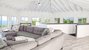 A spacious living room with a large sectional sofa, a ceiling fan, and a view of the outdoors through large windows.