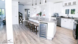 A modern kitchen with a central island, bar stools, and pendant lighting.