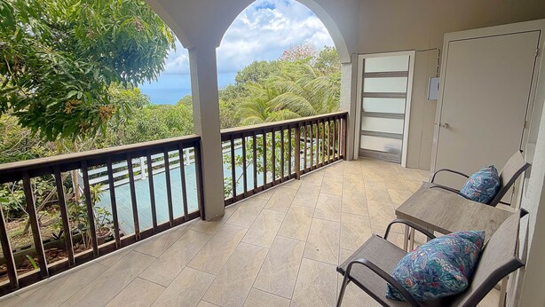 A balcony with a view of the ocean, a table with chairs, and a door.