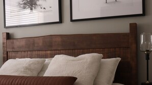 Ein ordentlich bezogenes Bett mit einem Holzkopfende, einem braunen Kopfkissen und einer weißen Decke.