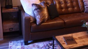 Ein Wohnzimmer mit einem braunen Ledersofa, einem Holztisch und zwei gerahmten Bildern von Stierköpfen an der Wand.