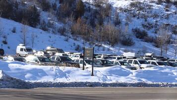 Un estacionamiento nevado con vehículos recreativos y automóviles, un letrero que dice "Bear Lot", y una carretera en primer plano.