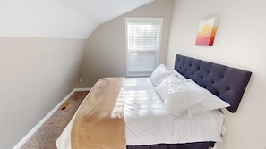 Ein Schlafzimmer mit Bett, einem Fenster mit Jalousien und einem Bild an der Wand.