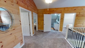 Une pièce aux murs en bois, avec un miroir rond et un escalier doté d’une rampe.