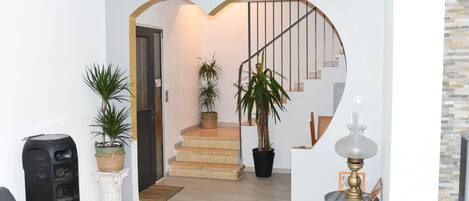 Stylish living space with a curved staircase, decorative archway, and cozy seating area.