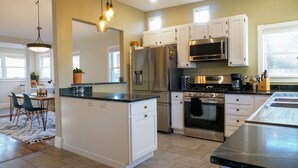 Una cocina moderna con armarios blancos, electrodomésticos de acero inoxidable y una isla central.