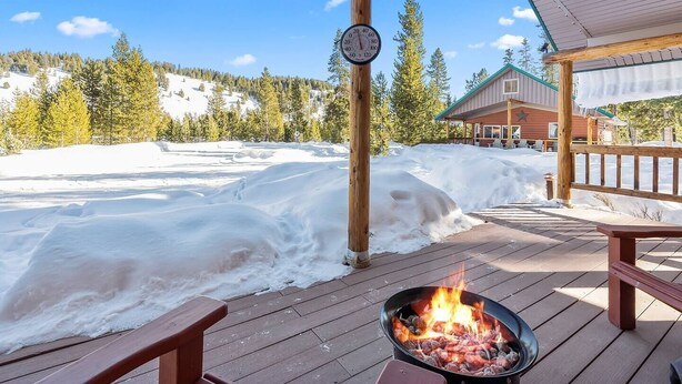 Une terrasse en bois avec un foyer, une horloge et, au fond, un bâtiment doté d’un toit végétalisé.