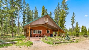 Une cabane dotée d’une véranda, d’un espace salon extérieur et offrant une vue sur la forêt environnante.