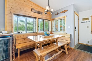 A cabin interior with a wooden bench table, a 'Cheers' sign, and a 'Welcome to Our Cabin' sign. - Stanley Stays - The Bonanza Cabin (Stanley)