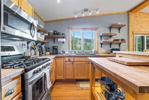 Une cuisine moderne avec des meubles en bois, une cuisinière en acier inoxydable et une grande fenêtre.