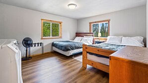 A bedroom with two beds, a washing machine, and a standing fan. - Stanley Stays - The Ponderosa Pine Cabin (Stanley)