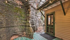 A rustic cabin with a wooden deck, a green door, and string lights. - Cozy Eureka Springs Cottage, Walk to Dtwn! (Eureka Springs)