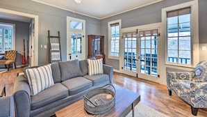 A spacious living room with a grey sofa, patterned armchair, and a wooden coffee table. - Cozy Eureka Springs Cottage, Walk to Dtwn! (Eureka Springs)