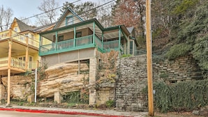 A two-story house with a balcony, stone foundation, and a red curb. - Cozy Eureka Springs Cottage, Walk to Dtwn! (Eureka Springs)