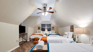 Une chambre d’hôtel avec deux lits, un ventilateur de plafond, une télévision et une fenêtre avec des stores.