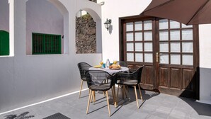 A patio with a table set for two, featuring a bottle, glasses, and a plate of food. - Sea Waves - 500M from the beach, Pool and Terrace By LVH (Puerto del Carmen)